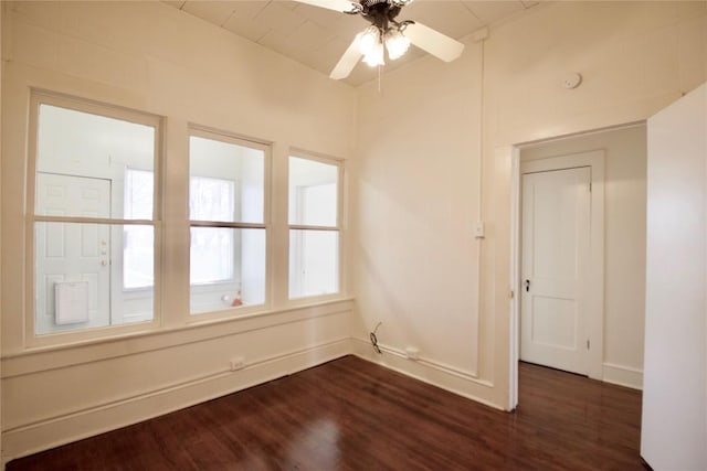 spare room featuring dark wood-type flooring, a ceiling fan, and baseboards