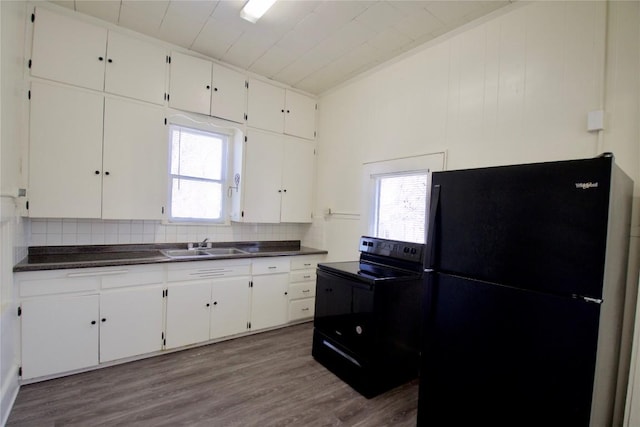 kitchen featuring dark countertops, white cabinetry, black appliances, and wood finished floors