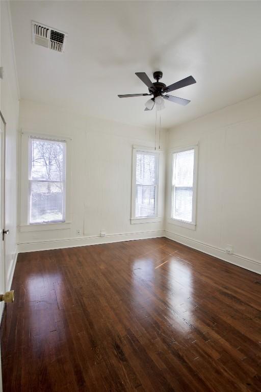 spare room featuring visible vents, ceiling fan, baseboards, and wood finished floors