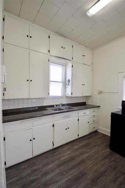 kitchen featuring dark countertops, white cabinetry, and a sink