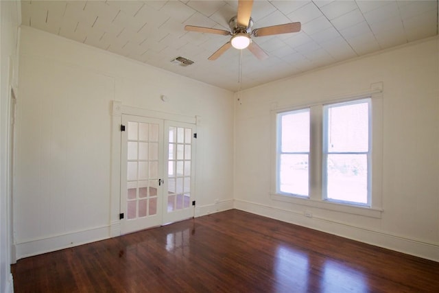 spare room with baseboards, visible vents, a ceiling fan, and wood finished floors