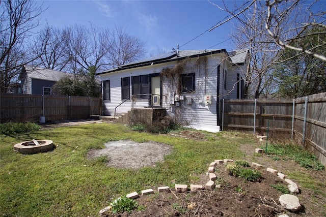 view of front of property with an outdoor fire pit, roof mounted solar panels, a fenced backyard, and a front yard