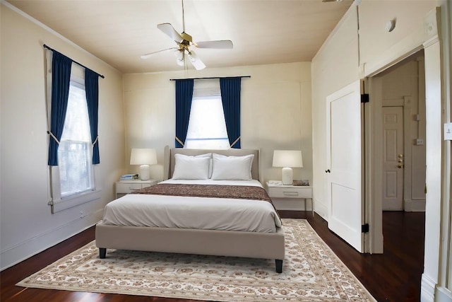 bedroom with dark wood-style flooring, multiple windows, ceiling fan, and baseboards