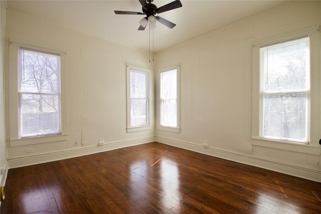 empty room with plenty of natural light, baseboards, dark wood finished floors, and a ceiling fan