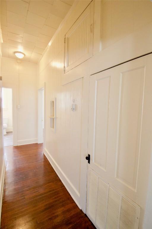 corridor featuring baseboards and dark wood finished floors