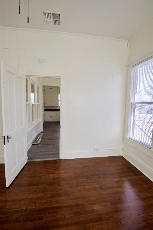 unfurnished room featuring baseboards, visible vents, and dark wood-type flooring