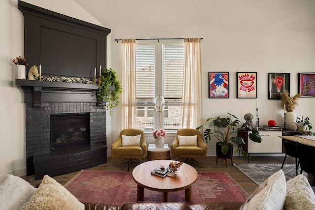 living area featuring lofted ceiling, a brick fireplace, and wood finished floors