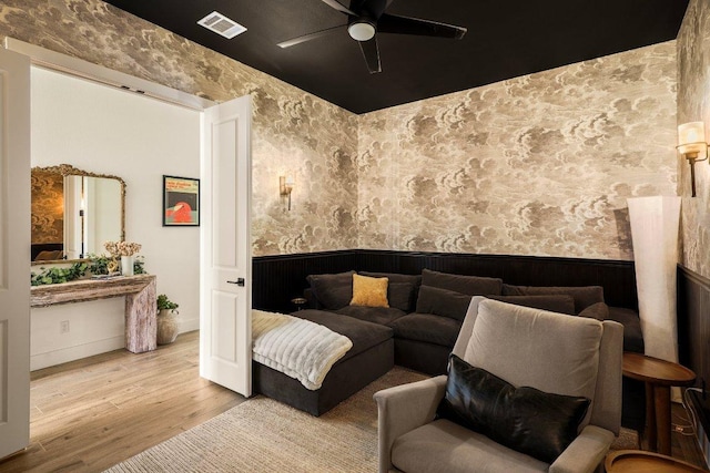 living area with wallpapered walls, visible vents, wood finished floors, and wainscoting