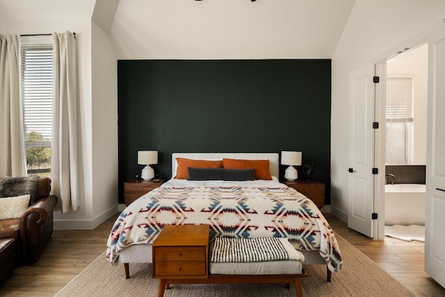 bedroom with lofted ceiling, baseboards, and wood finished floors