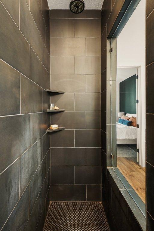 ensuite bathroom featuring a tile shower and connected bathroom