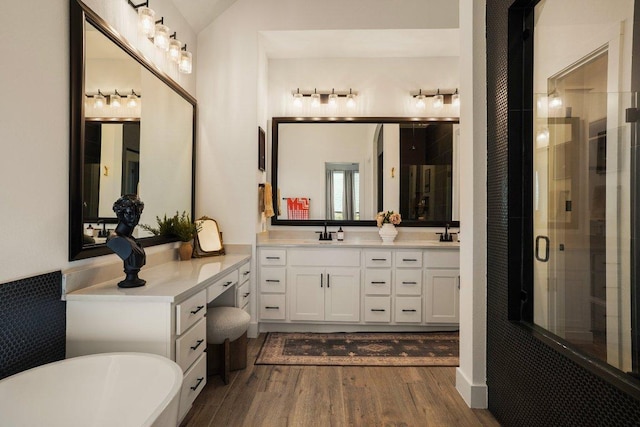 full bath with lofted ceiling, a sink, wood finished floors, a freestanding bath, and a stall shower