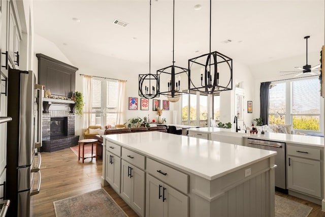 296 Running Bird Rd, Austin, TX 78737 - kitchen featuring a sink, lofted ceiling, wood finished floors, a kitchen island, and appliances with stainless steel finishes