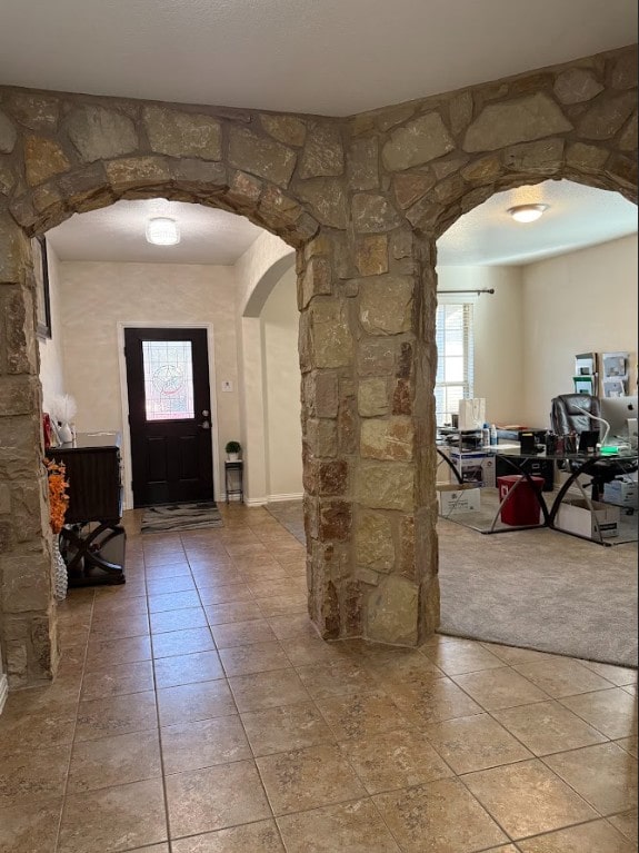 entrance foyer with arched walkways and light tile patterned floors