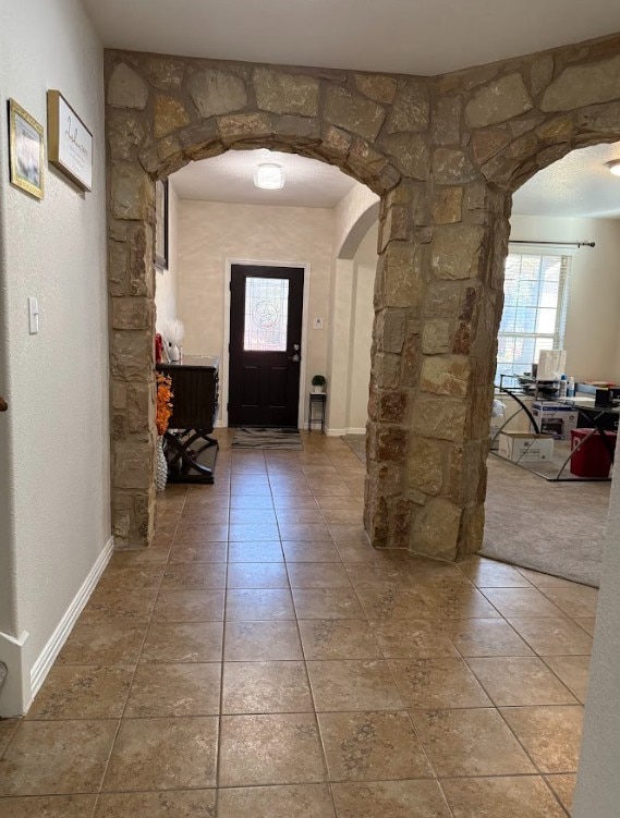 tiled foyer featuring baseboards and arched walkways