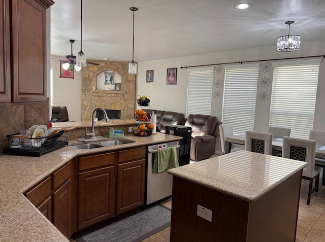 kitchen featuring open floor plan, a peninsula, stainless steel dishwasher, a fireplace, and a sink