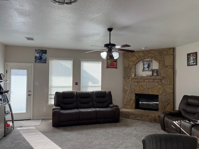 living room featuring a wealth of natural light, a fireplace, visible vents, and light colored carpet