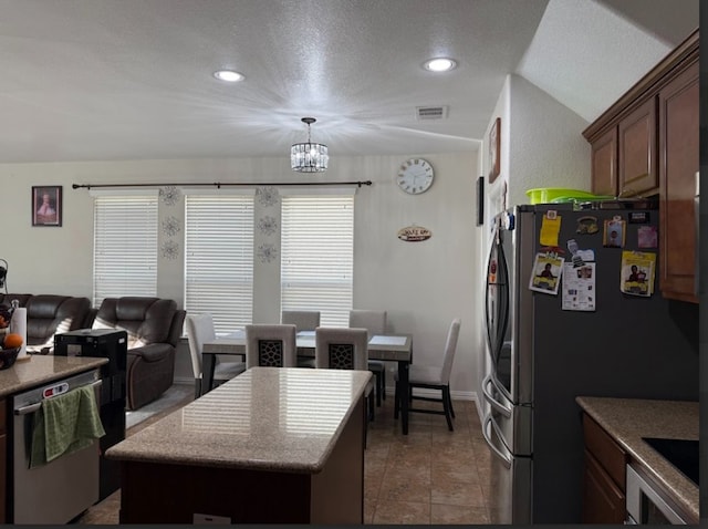 kitchen featuring a center island, a notable chandelier, appliances with stainless steel finishes, a textured ceiling, and tile patterned floors