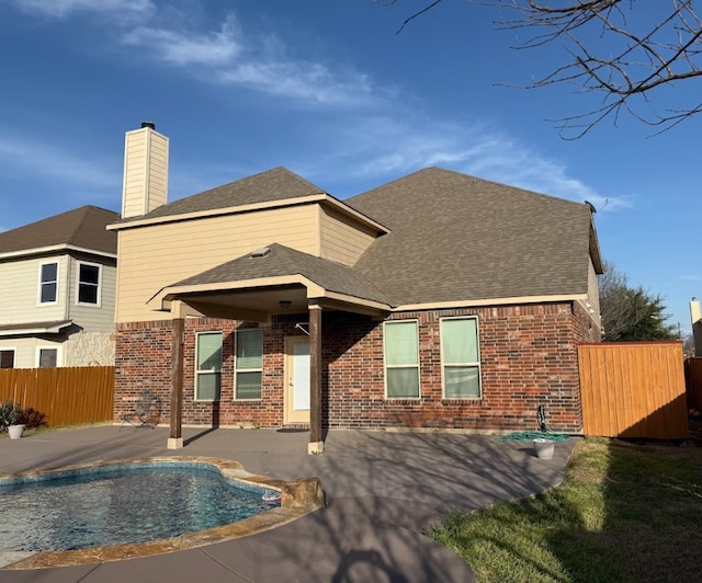 rear view of house with a fenced in pool, brick siding, roof with shingles, a patio area, and fence