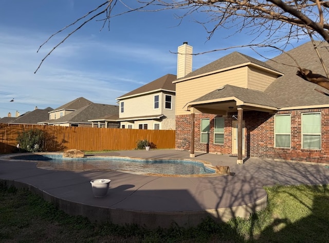 rear view of house featuring a fenced in pool, a patio area, brick siding, and fence