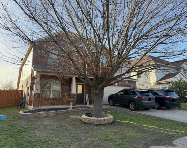 view of front of property featuring driveway, a garage, brick siding, fence, and a front yard