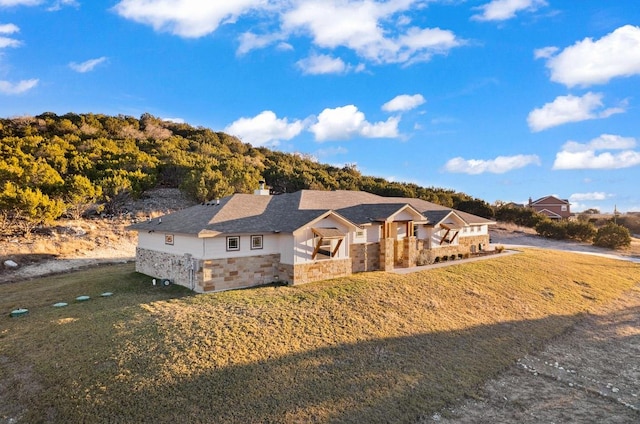 ranch-style house featuring stone siding, a chimney, and a front lawn