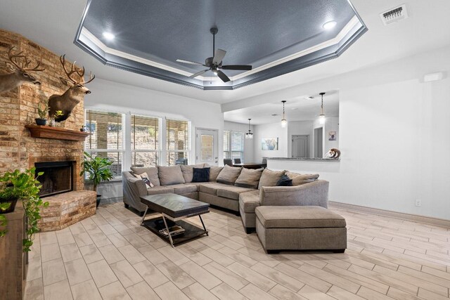 2807 Grimes Crossing Rd, Copperas Cove, TX 76522 - living room with a raised ceiling, ceiling fan, a fireplace, baseboards, and light wood-type flooring