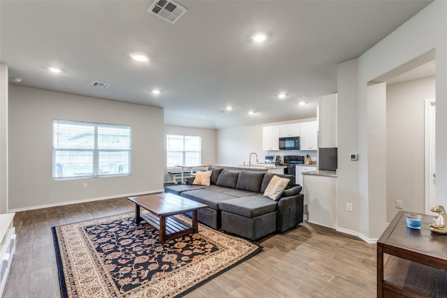 living area featuring light wood-type flooring, visible vents, and recessed lighting