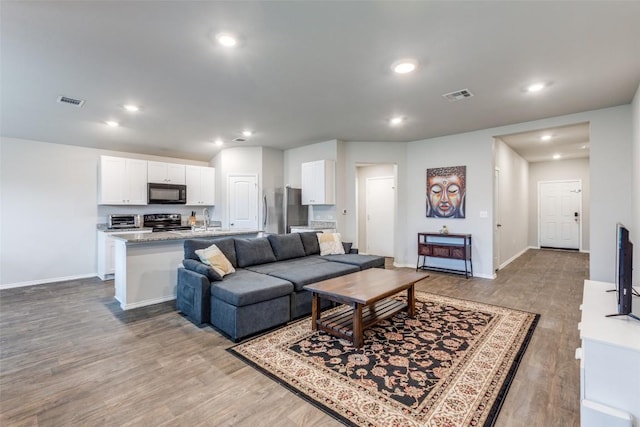 living room with light wood finished floors, visible vents, and recessed lighting