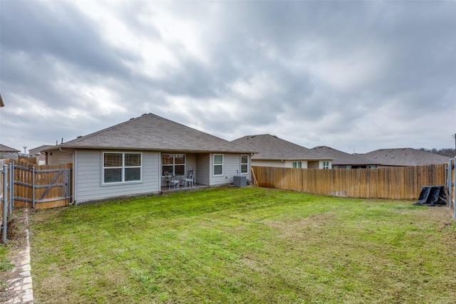 rear view of property featuring a fenced backyard, a shingled roof, cooling unit, and a yard