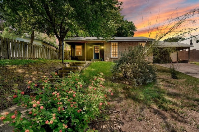 view of front of property with covered porch, fence, concrete driveway, and brick siding