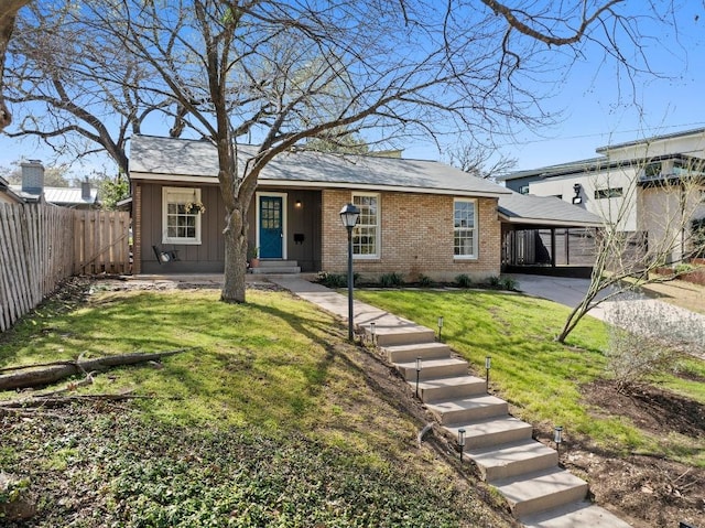 ranch-style house featuring a front yard, fence, an attached carport, and brick siding