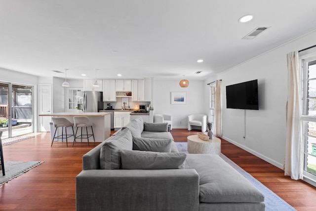 living room with baseboards, visible vents, wood finished floors, and recessed lighting