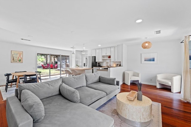 living area featuring recessed lighting, wood finished floors, visible vents, and baseboards