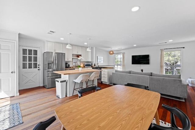 dining space featuring recessed lighting, visible vents, plenty of natural light, and wood finished floors