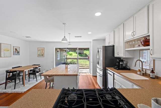 kitchen featuring light wood-type flooring, butcher block counters, white cabinets, and a sink