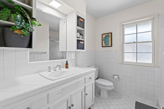 bathroom with tile patterned flooring, toilet, vanity, tile walls, and a shower