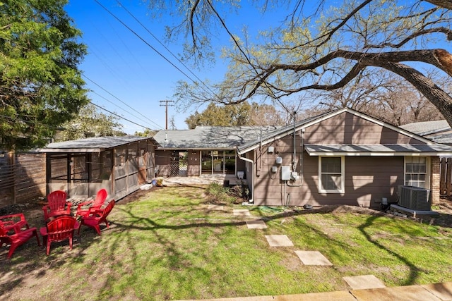 back of property with an outbuilding, a yard, and fence