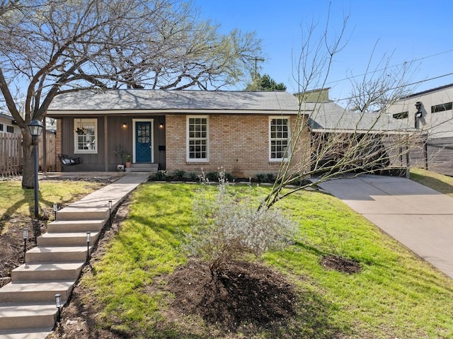 single story home with a front yard, brick siding, fence, and driveway