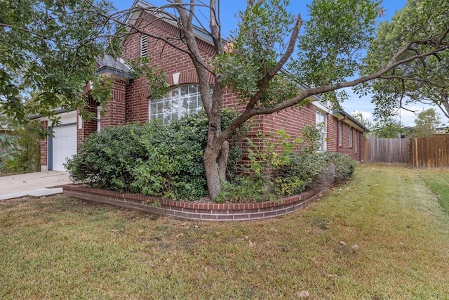 view of home's exterior with brick siding, a lawn, and fence