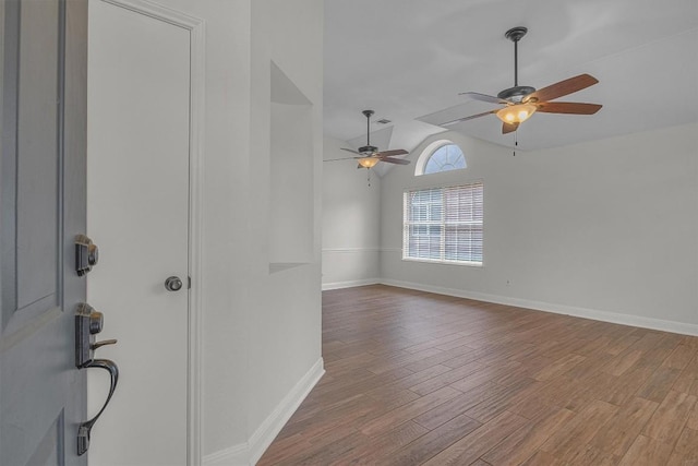 empty room with lofted ceiling, ceiling fan, wood finished floors, and baseboards