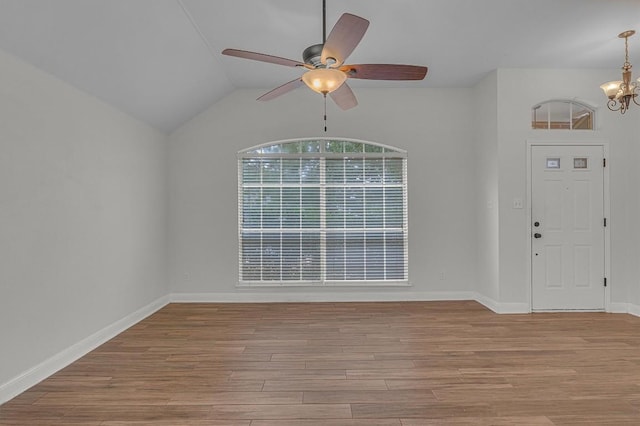 entryway featuring ceiling fan with notable chandelier, lofted ceiling, baseboards, and wood finished floors