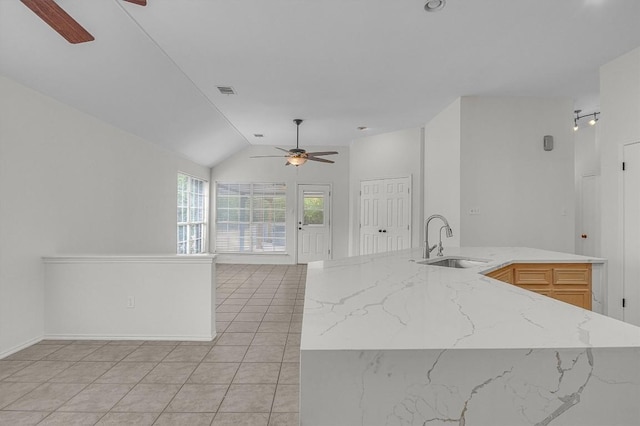 kitchen with light tile patterned floors, ceiling fan, light stone counters, open floor plan, and a sink