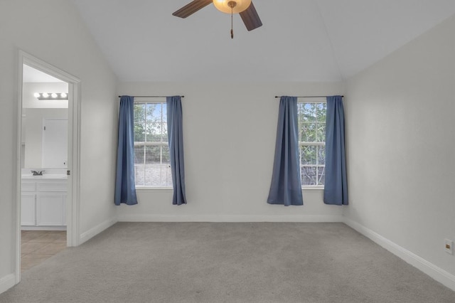 unfurnished room featuring lofted ceiling, a healthy amount of sunlight, and light colored carpet