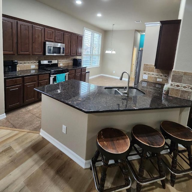 kitchen with a sink, tasteful backsplash, appliances with stainless steel finishes, and dark brown cabinets