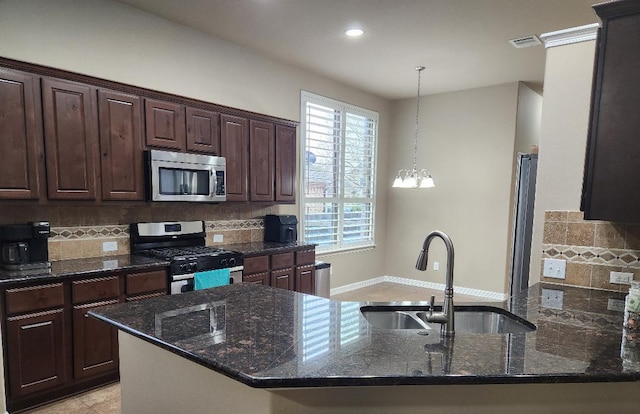 kitchen featuring dark stone countertops, dark brown cabinetry, appliances with stainless steel finishes, and a sink