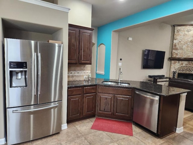 kitchen featuring a sink, dark brown cabinetry, dark stone countertops, and stainless steel appliances