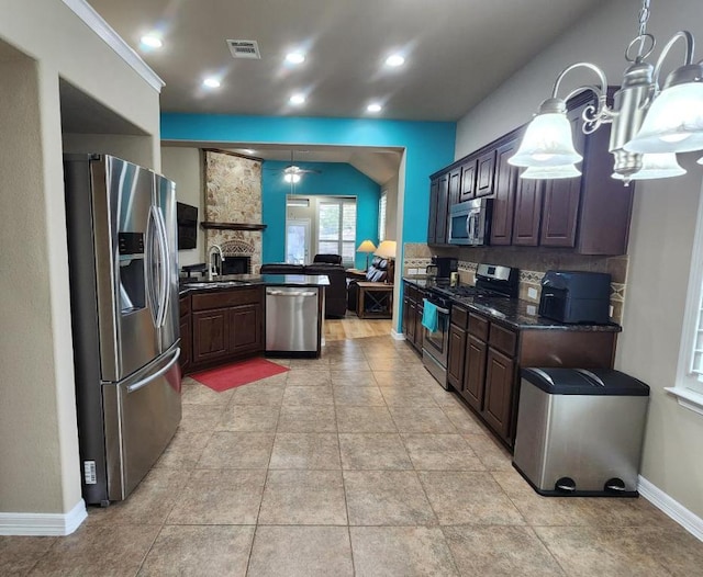 kitchen featuring visible vents, a sink, open floor plan, a peninsula, and appliances with stainless steel finishes