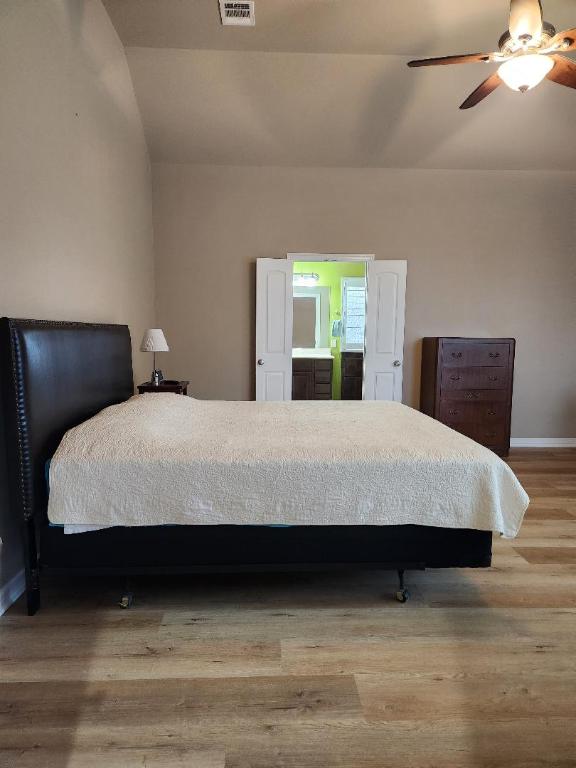 bedroom featuring a ceiling fan, wood finished floors, visible vents, baseboards, and vaulted ceiling