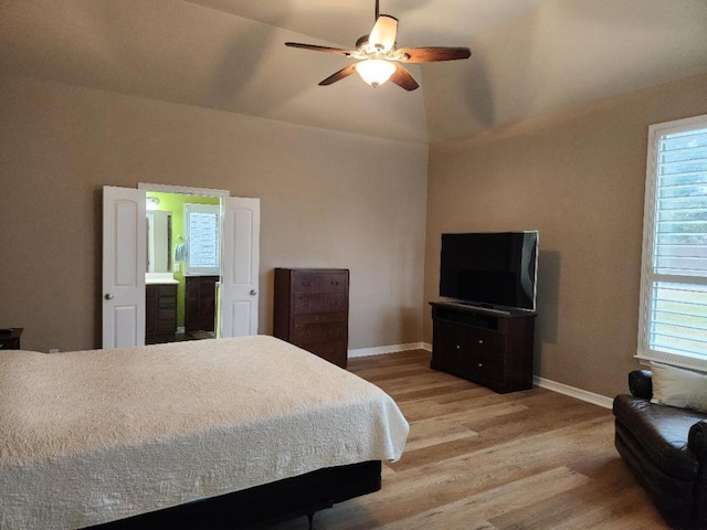 bedroom featuring a ceiling fan, baseboards, lofted ceiling, light wood-style floors, and ensuite bathroom