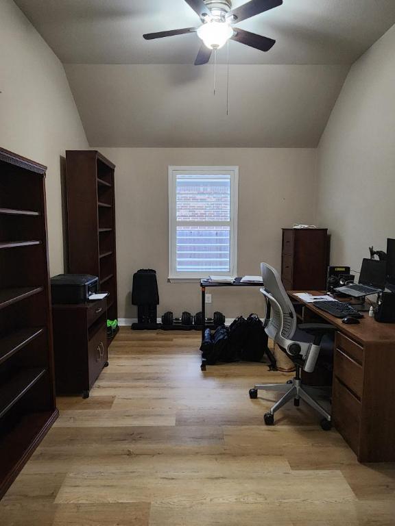 home office featuring light wood-type flooring, ceiling fan, and vaulted ceiling